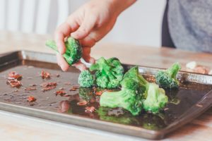 a baking sheet with bacon pieces and broccoli