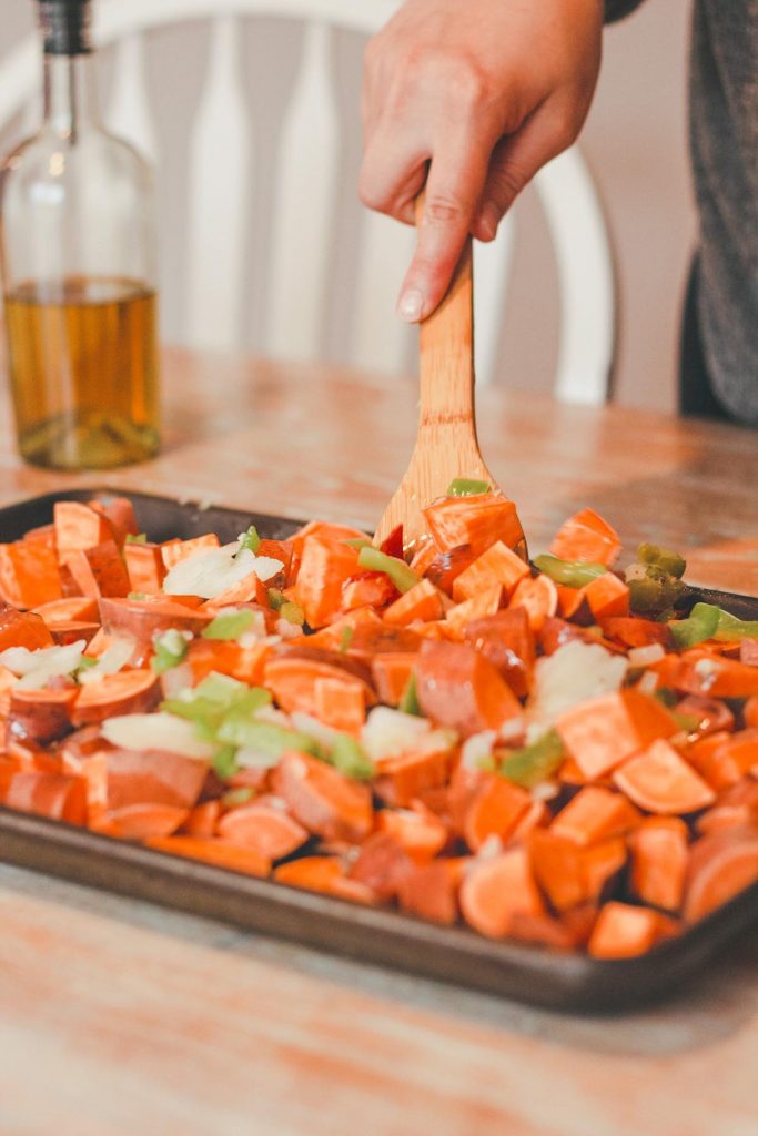 pan of sweet potatoes being tossed with oil