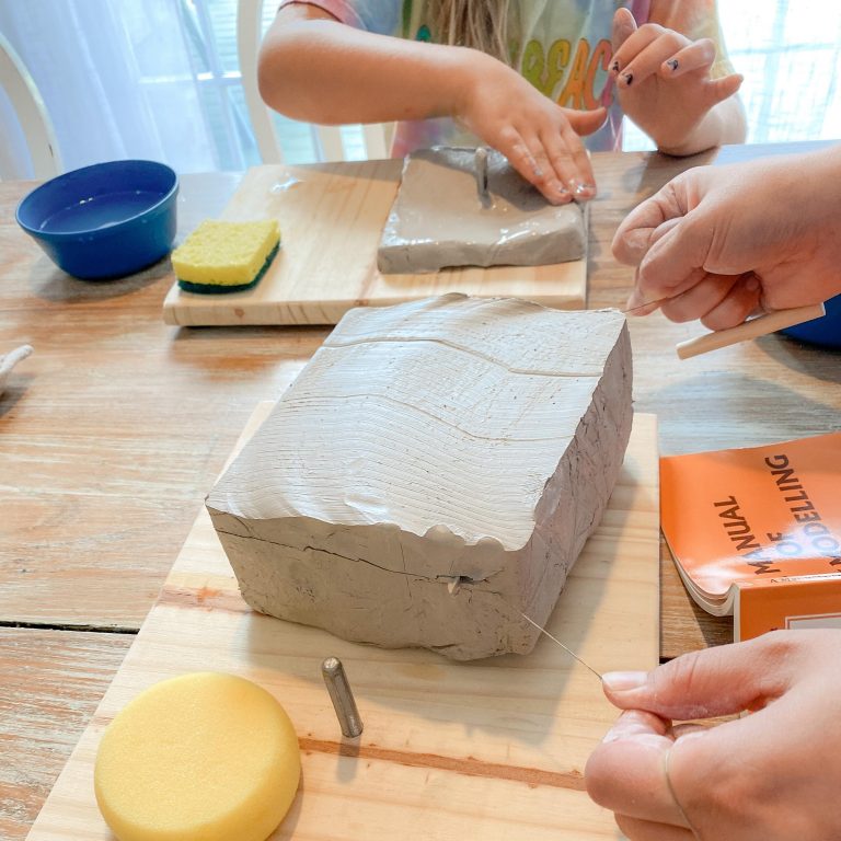 a woman cutting a slab of clay to teach her children clay modelling